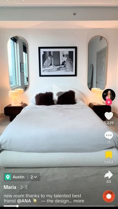 a bed with white sheets and pillows in a bedroom next to two mirrors on the wall