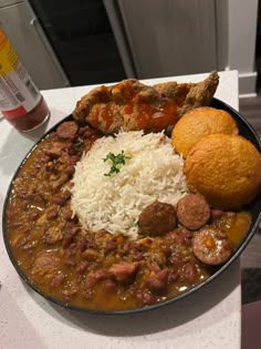 a bowl filled with meat and rice on top of a counter next to a drink