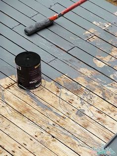 an umbrella and bucket on a wooden deck with water stains all over the flooring