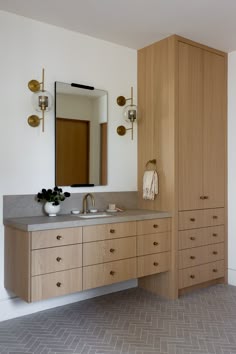 a bathroom with two sinks and wooden cabinets in it's own area, along with a large mirror on the wall