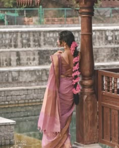 a woman in a pink sari standing next to a light pole with flowers on it