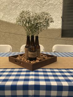 three brown bottles with flowers in them sitting on a blue and white checkered table cloth