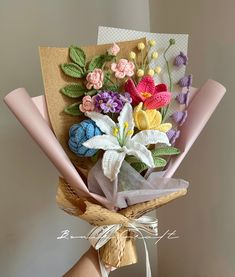 a person holding a bouquet of flowers on top of a wooden board with ribbon around it