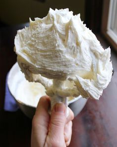 a person holding a spoon full of whipped cream