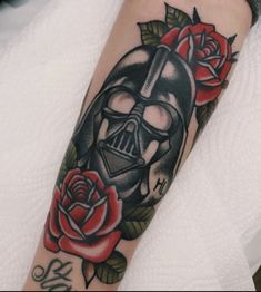 a tattoo with a darth vader helmet and roses on the arm is shown