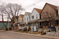 a row of houses on the corner of a street with trees in front of them