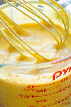 a blender filled with yellow liquid and whisk