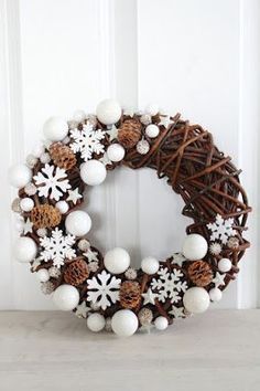 a wreath with white balls and snowflakes on it sitting in front of a door