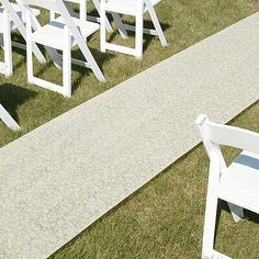 rows of white chairs sitting on top of a grass covered field