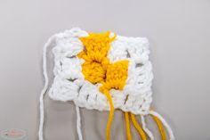 a white and yellow crocheted object with two strings