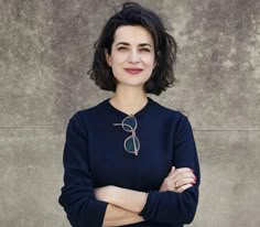 a woman standing with her arms crossed and looking at the camera