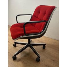 an office chair with a red upholstered seat and black frame, sitting on a hard wood floor