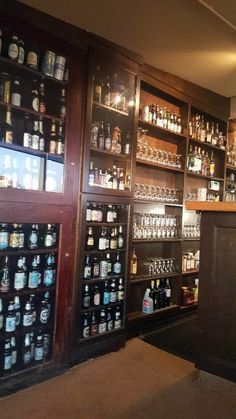 the bar is stocked with many different types of liquors and bottles on display in glass cases