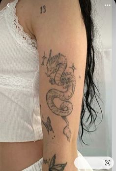 a woman's arm with tattoos on it and a dragon tattooed on the arm