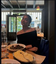 a woman sitting at a table with plates of food