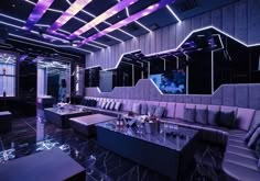 a living room with couches, tables and mirrors on the wall above them is lit by purple lights