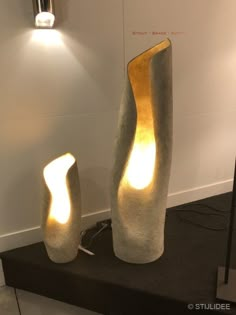 two large vases sitting on top of a black table next to each other in front of a white wall