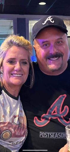 a man and woman are posing for a photo with beer glasses in hand, smiling at the camera