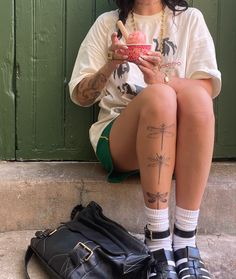 a woman sitting on the ground with her legs crossed and holding a cup in front of her