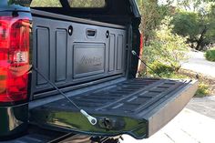 the back end of a pickup truck with its tail lights on and cargo compartment open