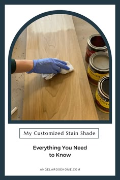 a person with gloves on cleaning a wooden table next to some paint cans and a brush