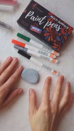 someone's hand next to some markers and pens