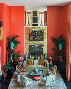 the living room is painted bright orange and has two couches, chairs, and a fireplace