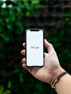 a person holding up a smart phone with the google logo on it's screen