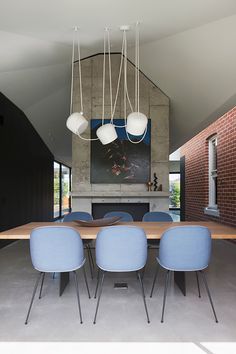 a dining room table with blue chairs and hanging lights