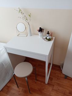 a small white desk and chair in a room with wood floors, walls and flooring