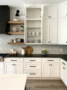 an open kitchen cabinet with white cabinets and black counter tops is featured in this article