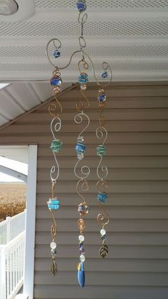 a wind chime hanging from the side of a house with beads and shells on it