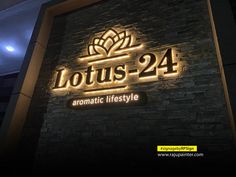 the sign for lotus - 24 is lit up in front of a dark brick wall