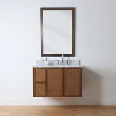 a bathroom vanity with two sinks and a mirror on the wall above it, in front of a white wall