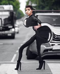 a woman in black is standing next to a car