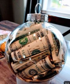 a glass ornament filled with money sitting on top of a wooden table