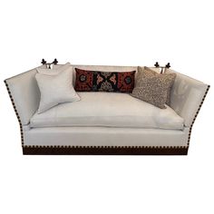 a white couch with two pillows on it and some other decorative items around the edges