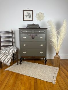 a dresser and chair in a room with wood floors, rugs and pictures on the wall