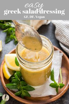 a spoon is pouring dressing into a jar with lemons and herbs on the side