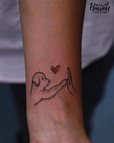 a woman's wrist tattoo with a dog holding a heart on her left arm