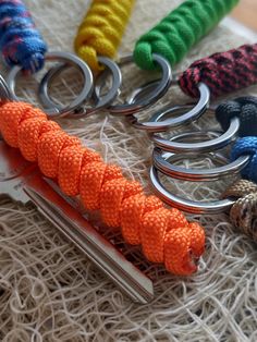 several different colored roped objects are laying on a white surface and one has a pair of scissors in it