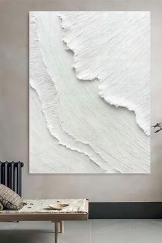 a white painting hanging on the wall above a bed in a room with a radiator