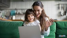 a woman and child sitting on a green couch looking at a laptop computer while laughing