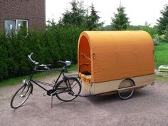 a bike is parked next to an orange covered trailer with a bicycle in the front