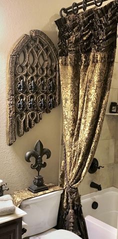 a white toilet sitting next to a bath tub under a window covered in gold curtains