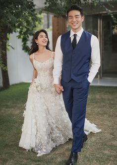 a bride and groom walking through the grass