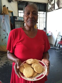 an older woman holding a plate with cookies on it