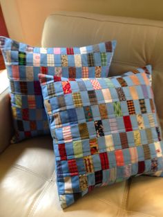 two pillows are sitting on a couch with the same color and pattern as they appear to be made out of fabric