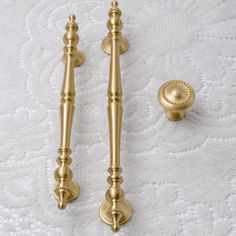 two golden door handles and knobs on a white towel or bed sheet with an intricate design