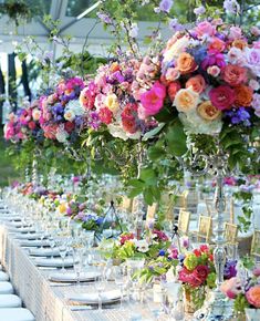 a long table set with flowers and place settings for an outdoor dinner party or celebration